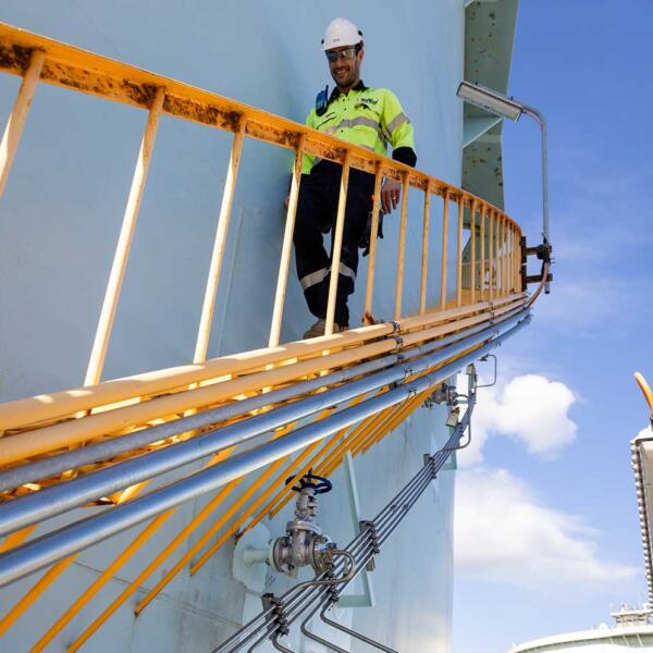 Industrial electrician in Geelong walking down staircase on side of tank